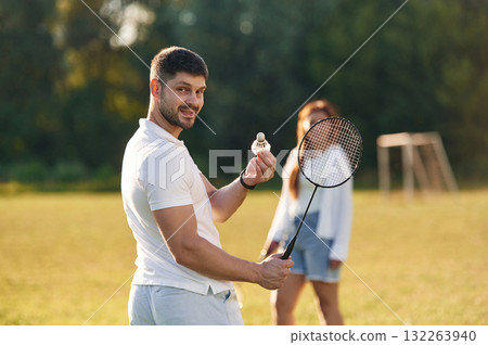 Weekend activities. Man with woman are playing badminton on the field 132263940