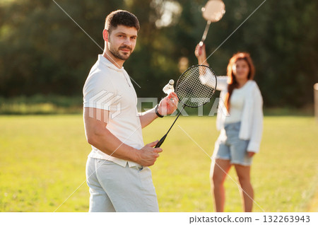 Weekend activities. Man with woman are playing badminton on the field Weekend activities. Man with woman are playing badminton on the field 132263943