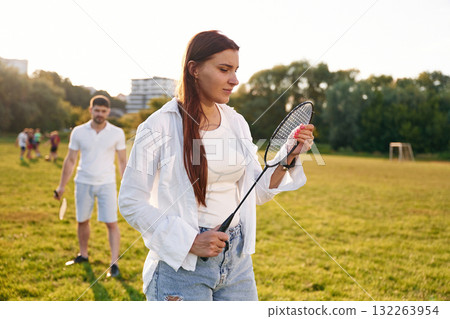 Taking a rest, standing. Man with woman are playing badminton on the field 132263954