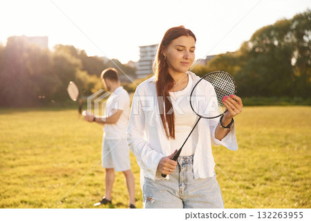 Taking a rest, standing. Man with woman are playing badminton on the field Taking a rest, standing. Man with woman are playing badminton on the field 132263955