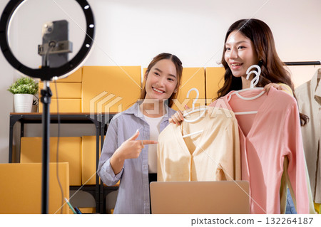 Two young asian woman live streaming online clothing store while showing clothing with smartphone. Two young asian woman live streaming online clothing store while showing clothing with smartphone. 132264187