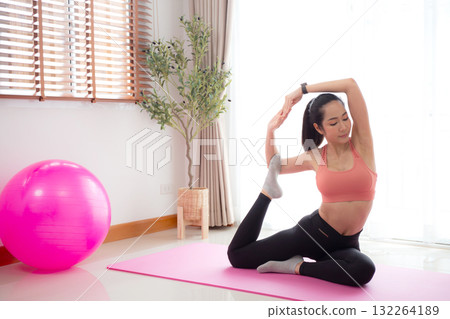 Young asian woman practicing Yoga with stretching muscle back on yoga mat in living room. 132264189