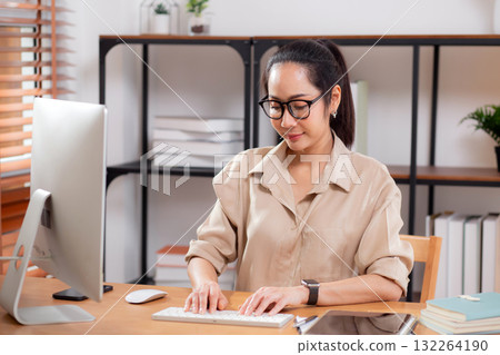 Happiness young businesswoman using desktop computer on desk in living room at home office. 132264190