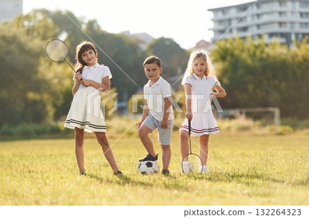 Soccer ball and badminton rackets. Happy kids are on the summer field Soccer ball and badminton rackets. Happy kids are on the summer field 132264323