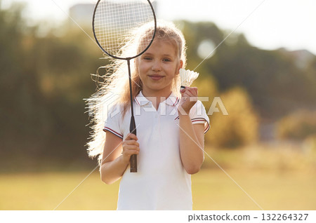 Cute little girl is with badminton racket on the field Cute little girl is with badminton racket on the field 132264327