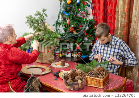 Grandma and grandson make a Christmas wreath together at home. Making decorations in winter. 132264705