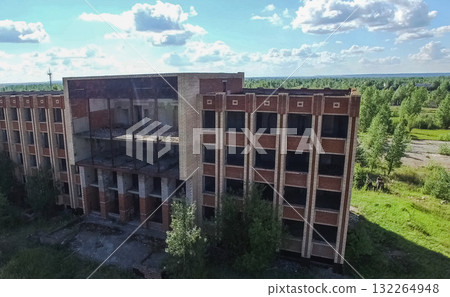 An old abandoned high rise building, overgrown with trees and gr 132264948