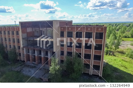 An old abandoned high rise building, overgrown with trees and gr An old abandoned high rise building, overgrown with trees and gr 132264949