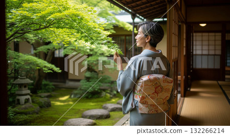 一位身穿和服的日本女子從陽台望向花園,綠色的楓葉 一位身穿和服的日本女子從陽台望向花園,綠色的楓葉 132266214