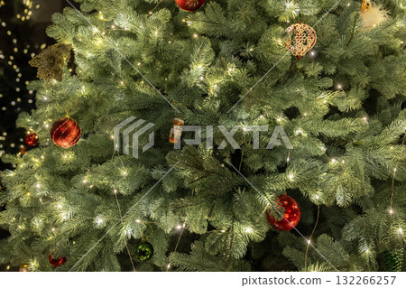 Close-up of a beautifully decorated Christmas tree with sparkling lights and colorful ornaments, radiating warmth and holiday cheer. 132266257