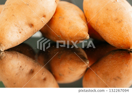 Sweet potatoes lying on reflective table surface natural light food photo 132267094