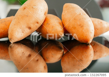 Several sweet potatoes on glossy black table clean healthy food concept and natural light 132267095