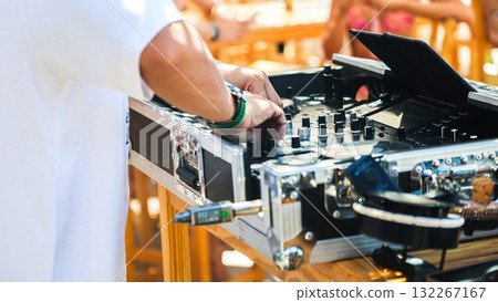 A DJ musician near the music console at a disco on the beach A DJ musician near the music console at a disco on the beach 132267167