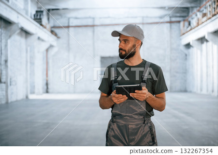 Black digital tablet in hands. Male worker is in the empty warehouse 132267354