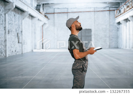 Black digital tablet in hands. Male worker is in the empty warehouse Black digital tablet in hands. Male worker is in the empty warehouse 132267355