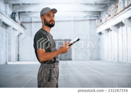 Black digital tablet in hands. Male worker is in the empty warehouse Black digital tablet in hands. Male worker is in the empty warehouse 132267356