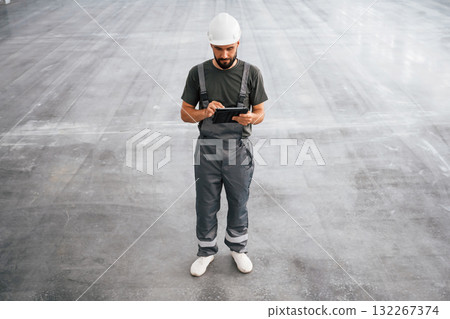 View from the front, with digital tablet in hands. Male worker is in the empty warehouse 132267374