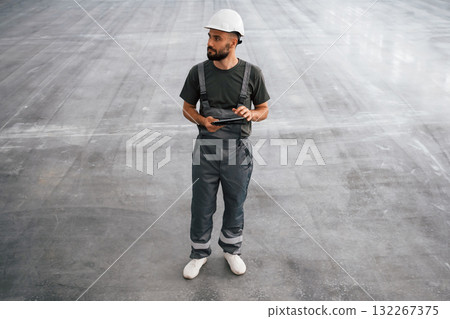 View from the front, with digital tablet in hands. Male worker is in the empty warehouse 132267375