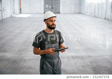 View from the front, with digital tablet in hands. Male worker is in the empty warehouse View from the front, with digital tablet in hands. Male worker is in the empty warehouse 132267378