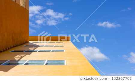 Modern yellow building with blue sky and geometric architecture perspective 132267702