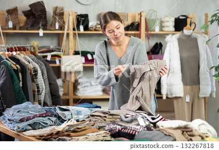 Young woman chooses sweater in clothing store Young woman chooses sweater in clothing store 132267818