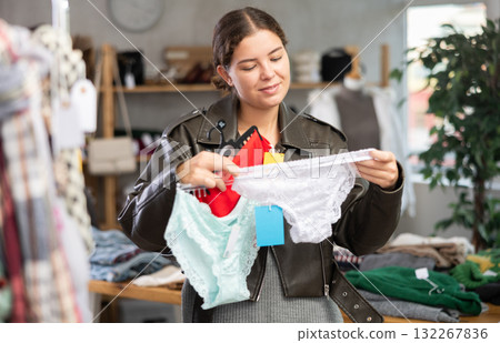 Female shopper selects panties in fashionable clothing boutique. Female shopper selects panties in fashionable clothing boutique. 132267836