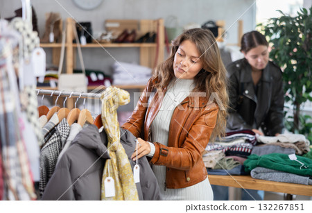 Interested happy young girl standing in clothing shop and looking something on sale of winter clothing collection 132267851