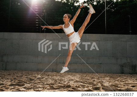 Up in the air, jumping. Young skinny fitness woman is outdoors 132268037