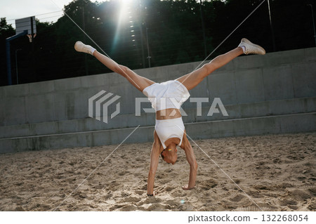 Upside down, doing the tricks. Young skinny fitness woman is outdoors Upside down, doing the tricks. Young skinny fitness woman is outdoors 132268054