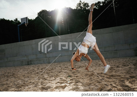 Upside down, doing the tricks. Young skinny fitness woman is outdoors 132268055