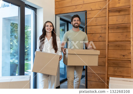 Man and woman carrying boxes into a new accommodation and feeling excited Man and woman carrying boxes into a new accommodation and feeling excited 132268108