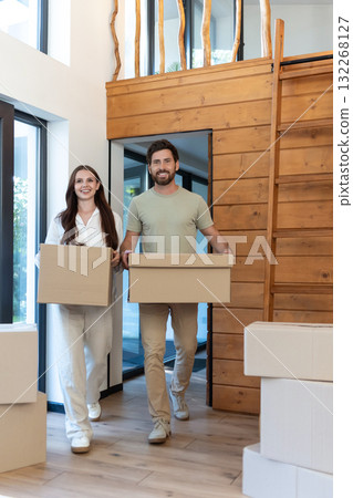 Man and woman carrying boxes into a new accommodation and feeling excited Man and woman carrying boxes into a new accommodation and feeling excited 132268127