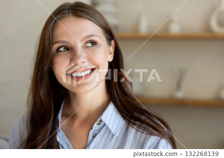 Woman posing in light room looking smiling away in home living area Woman posing in light room looking smiling away in home living area 132268139