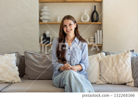Cheerful brunette woman sitting casually in domestic space 132268166