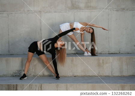 On the cement structure, exercise. Two sportive women are outdoors together On the cement structure, exercise. Two sportive women are outdoors together 132268262