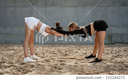 Side view, holding each other hands, exercise. Two sportive women are outdoors together Side view, holding each other hands, exercise. Two sportive women are outdoors together 132268271
