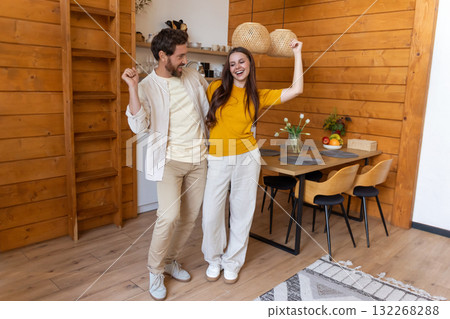 Cute couple feeling excited and joyful while dancing in the kitchen Cute couple feeling excited and joyful while dancing in the kitchen 132268288