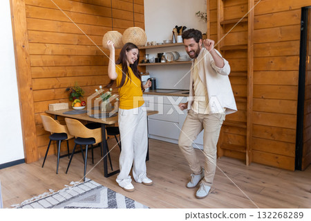 Cute couple feeling excited and dancing in the kitchen Cute couple feeling excited and dancing in the kitchen 132268289