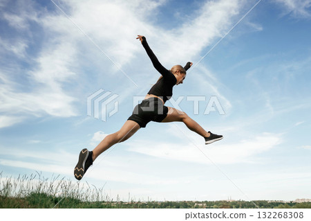 Jumping against the sky. Beautiful fitness woman in sport clothes is outdoors Jumping against the sky. Beautiful fitness woman in sport clothes is outdoors 132268308