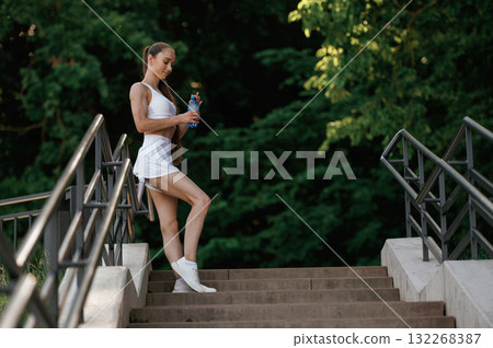 With bottle of water. Young skinny fitness woman is outdoors 132268387