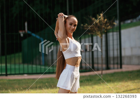 Posing, relaxed. Young skinny fitness woman is outdoors Posing, relaxed. Young skinny fitness woman is outdoors 132268393