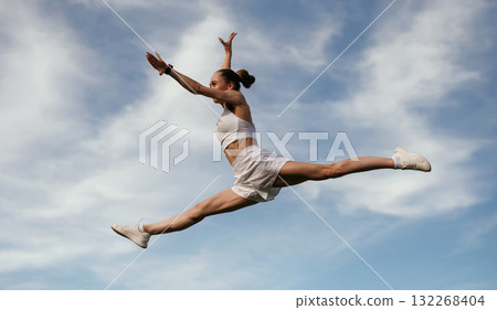 Blue sky with clouds, jumping. Young skinny fitness woman is outdoors 132268404