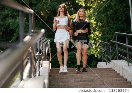 Walking the stairs. Two sportive women are outdoors together Walking the stairs. Two sportive women are outdoors together 132268474