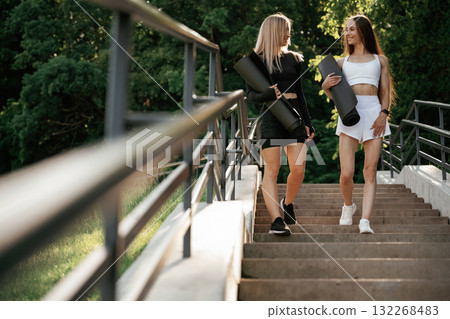 Railings and stairs. Two sportive women are outdoors together 132268483