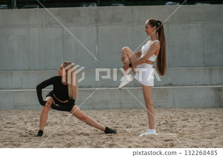 Legs exercise, warm up. Two sportive women are outdoors together 132268485