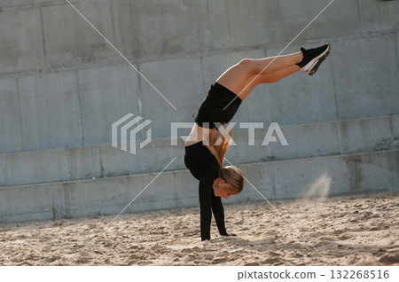 Doing tricks. Beautiful fitness woman in sport clothes is outdoors Doing tricks. Beautiful fitness woman in sport clothes is outdoors 132268516