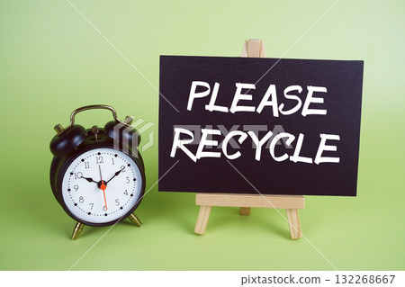 Please Recycle text with easel and alarm clock on green background Please Recycle text with easel and alarm clock on green background 132268667