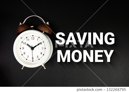 Saving Money text with alarm clock on black background Saving Money text with alarm clock on black background 132268795