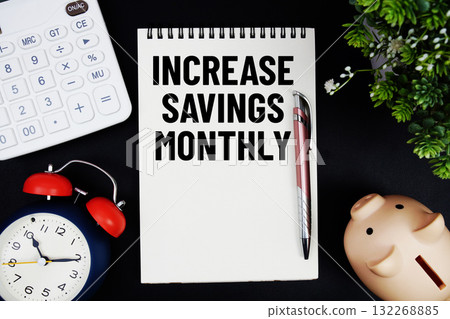 Increase Savings Monthly text with calculator with alarm clock and piggy bank on black background 132268885