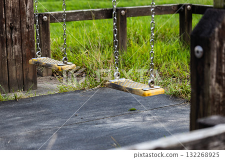 An empty swing in the park, public playground equipment 132268925